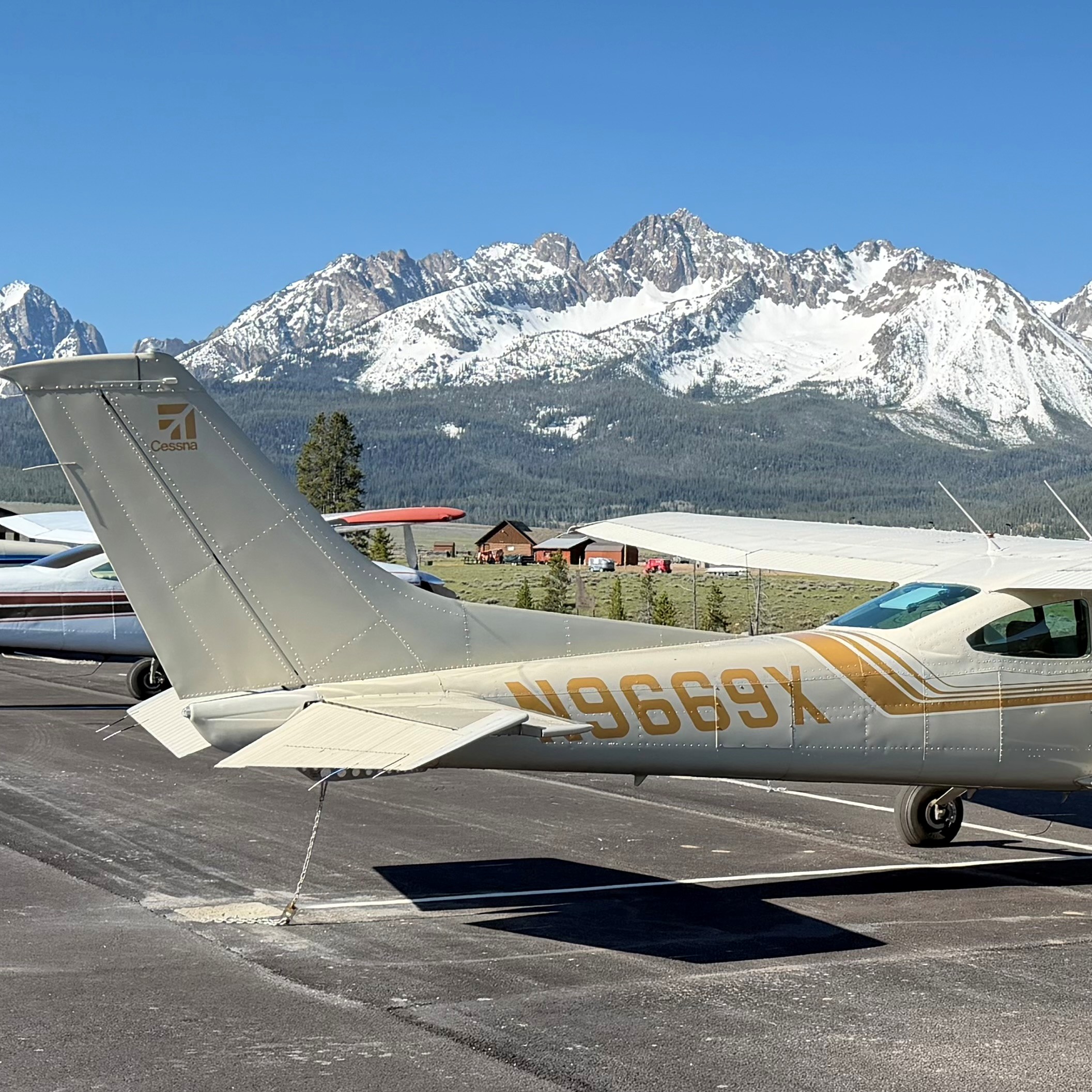 Cessna 182R N9669X parked on the ramp with snow-covered mountains in the background